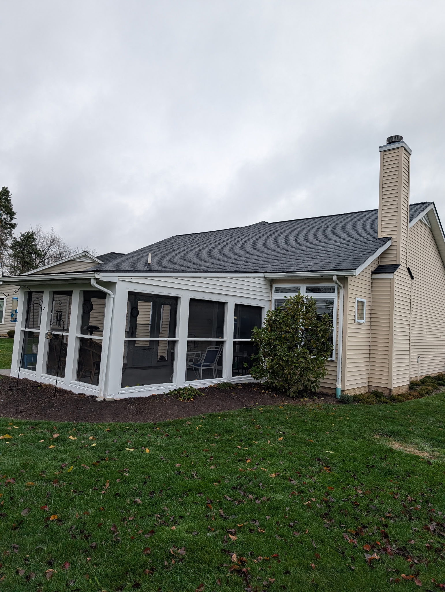 Completed charcoal roof replacement on a tan home with screened porch — Northeast Ohio