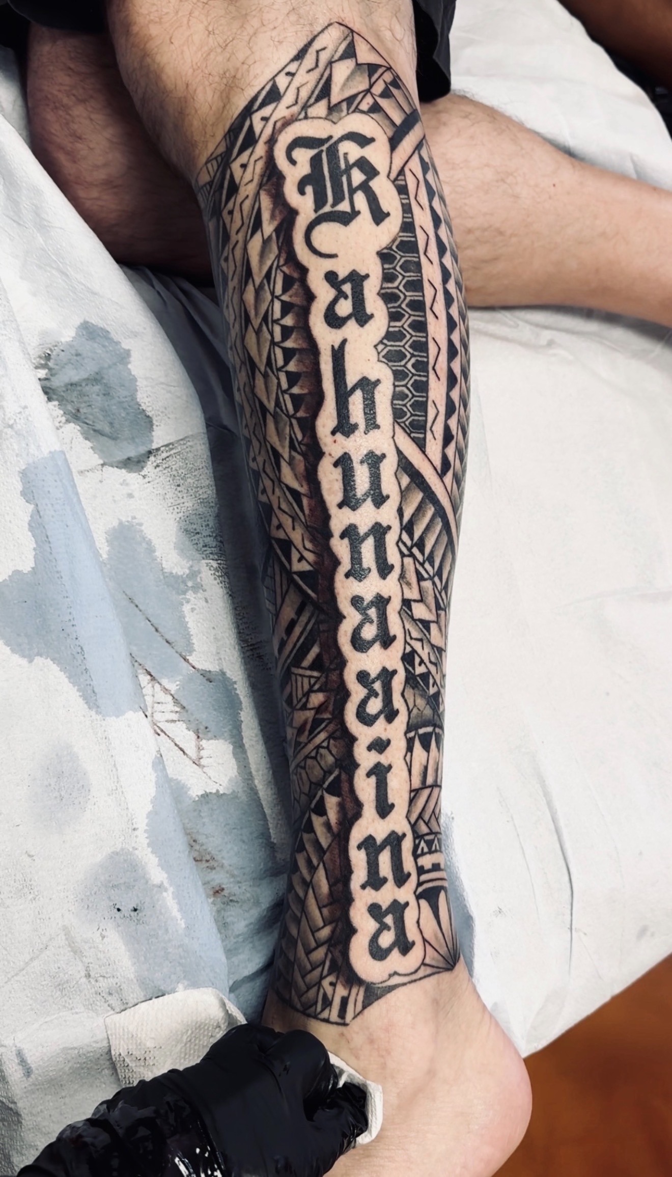 Polynesian calf tattoo with name lettering by Marc Cabos