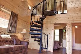 Interior of a cabin at Cabins of Mackinaw showing the knotty pine walls and a spiral staircase leading to a loft