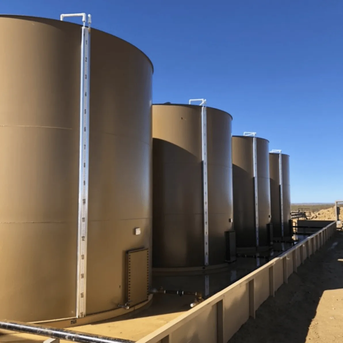 Large oilfield storage tanks in Oklahoma field with external tank gauge system installed