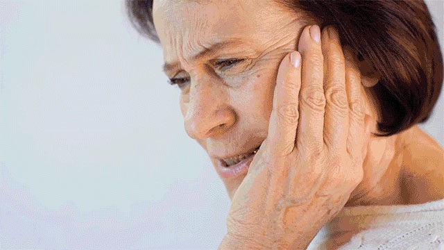 Woman holding her jaw in discomfort, considering dental relief options