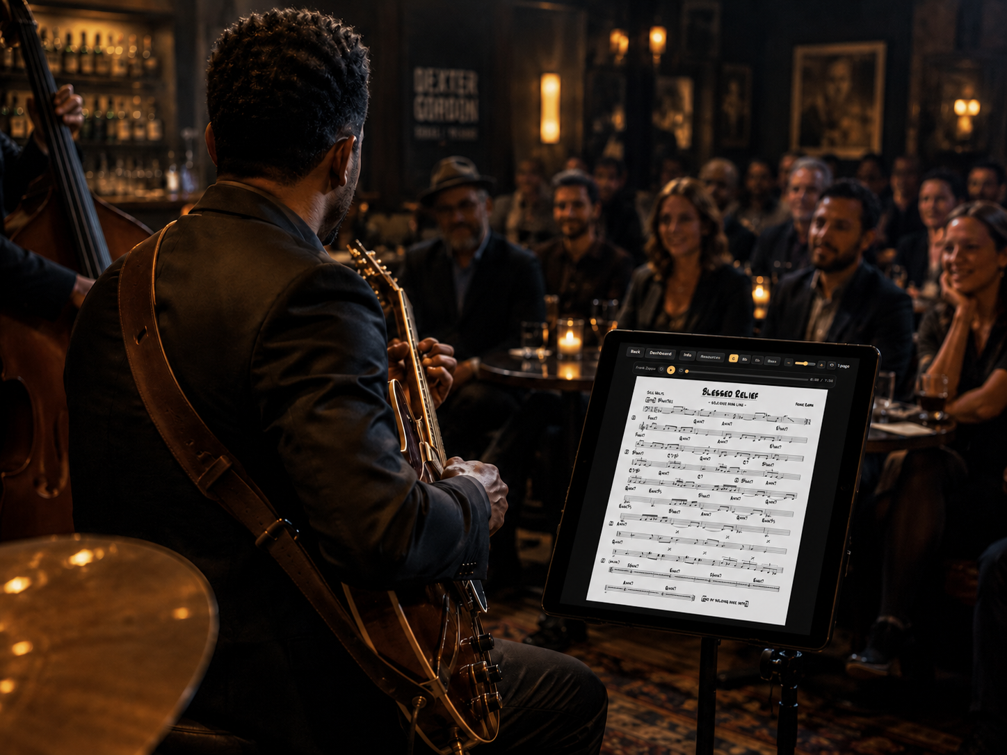 Guitarist performing with a JazzMember chart on a tablet in a warm jazz club setting