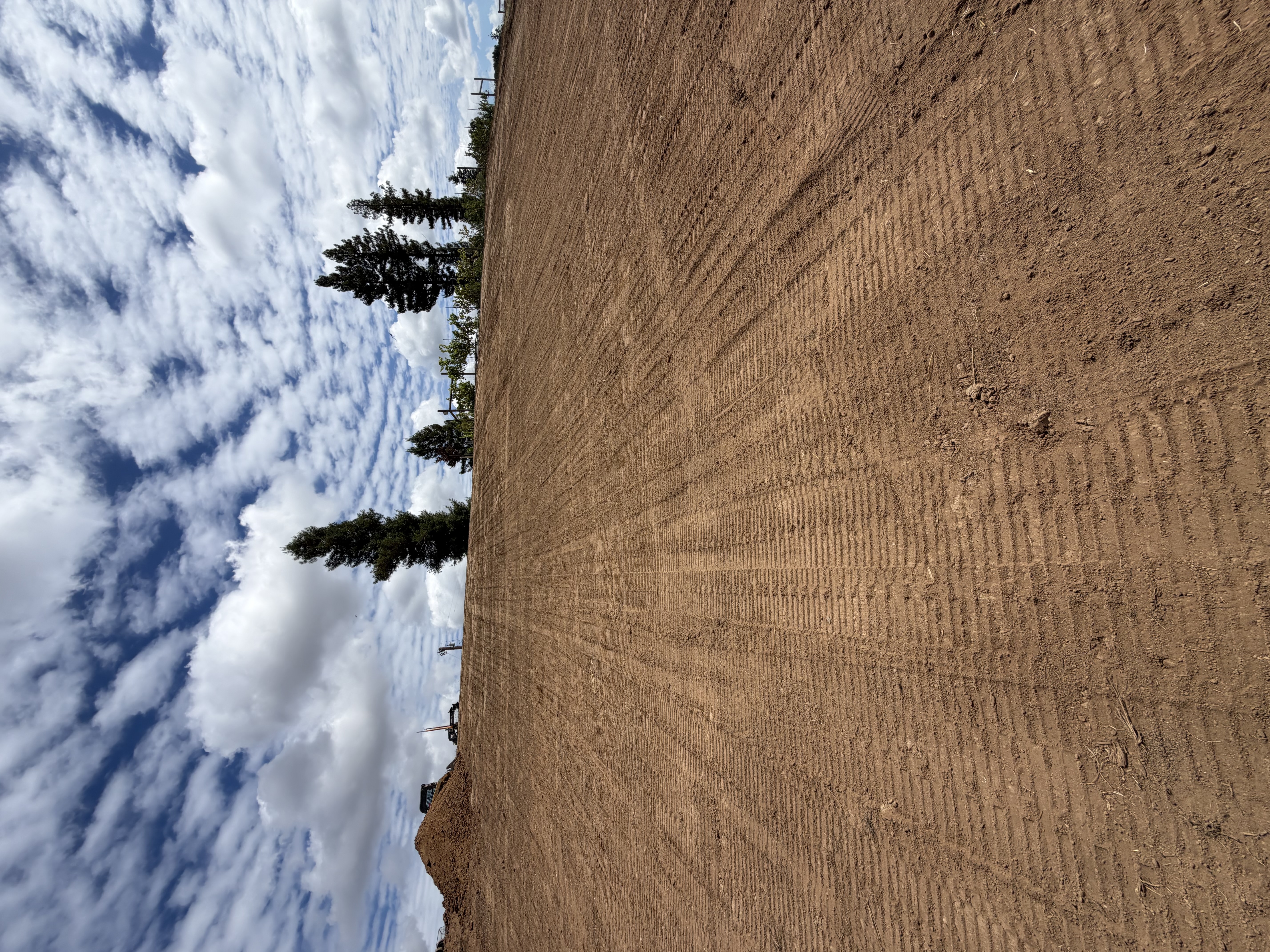 Graded earthwork site under a cloud-filled sky