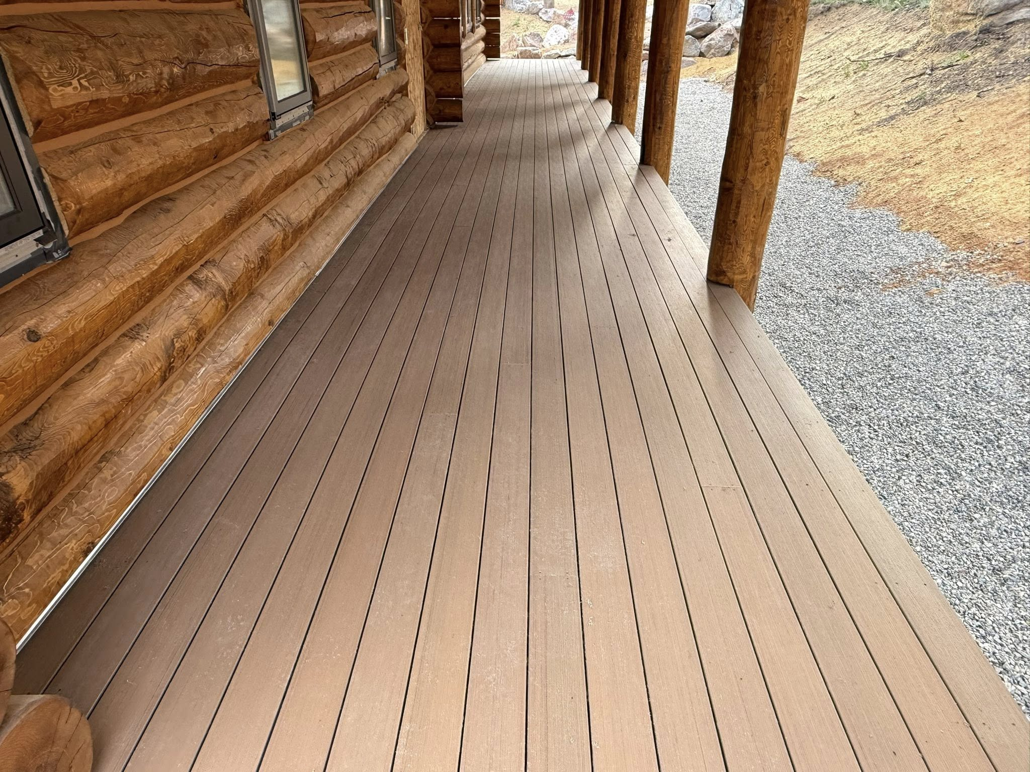 Log cabin wrap-around deck with composite decking and log post columns