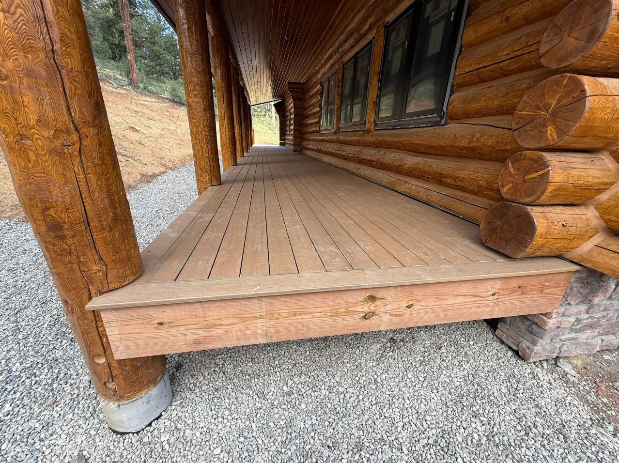 Log cabin covered porch with composite deck boards and natural log posts