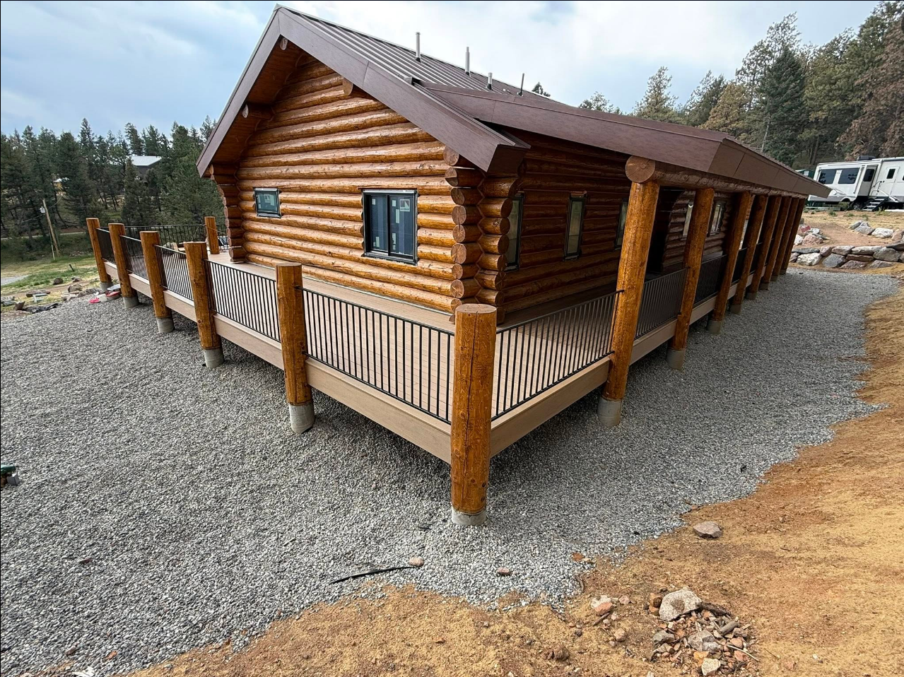 Full log cabin exterior with wraparound composite deck and metal railing