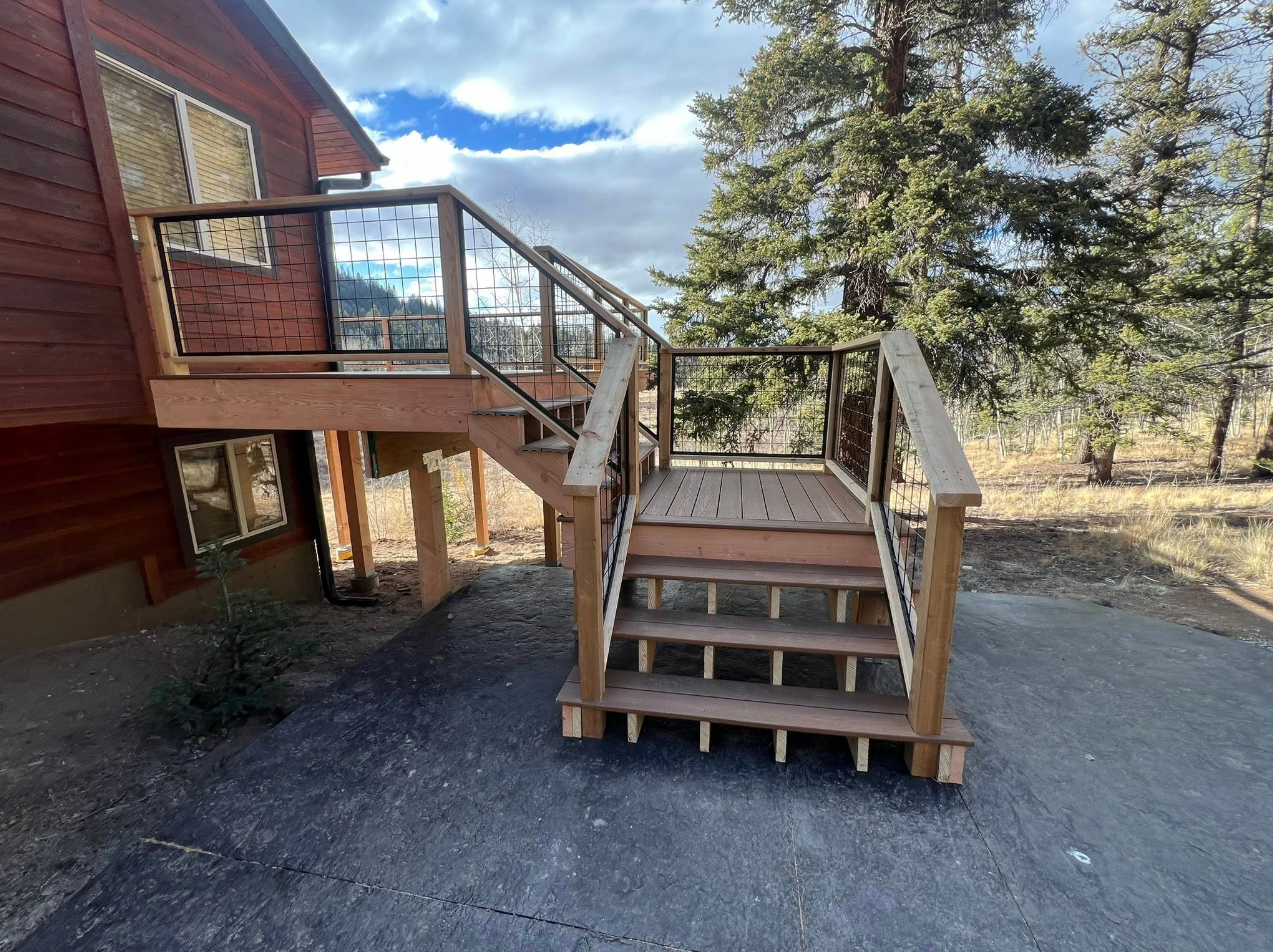 Elevated deck with wire mesh railing and staircase on mountain property