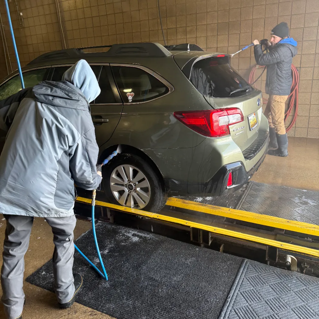 Team members pre-spraying a vehicle inside the wash bay