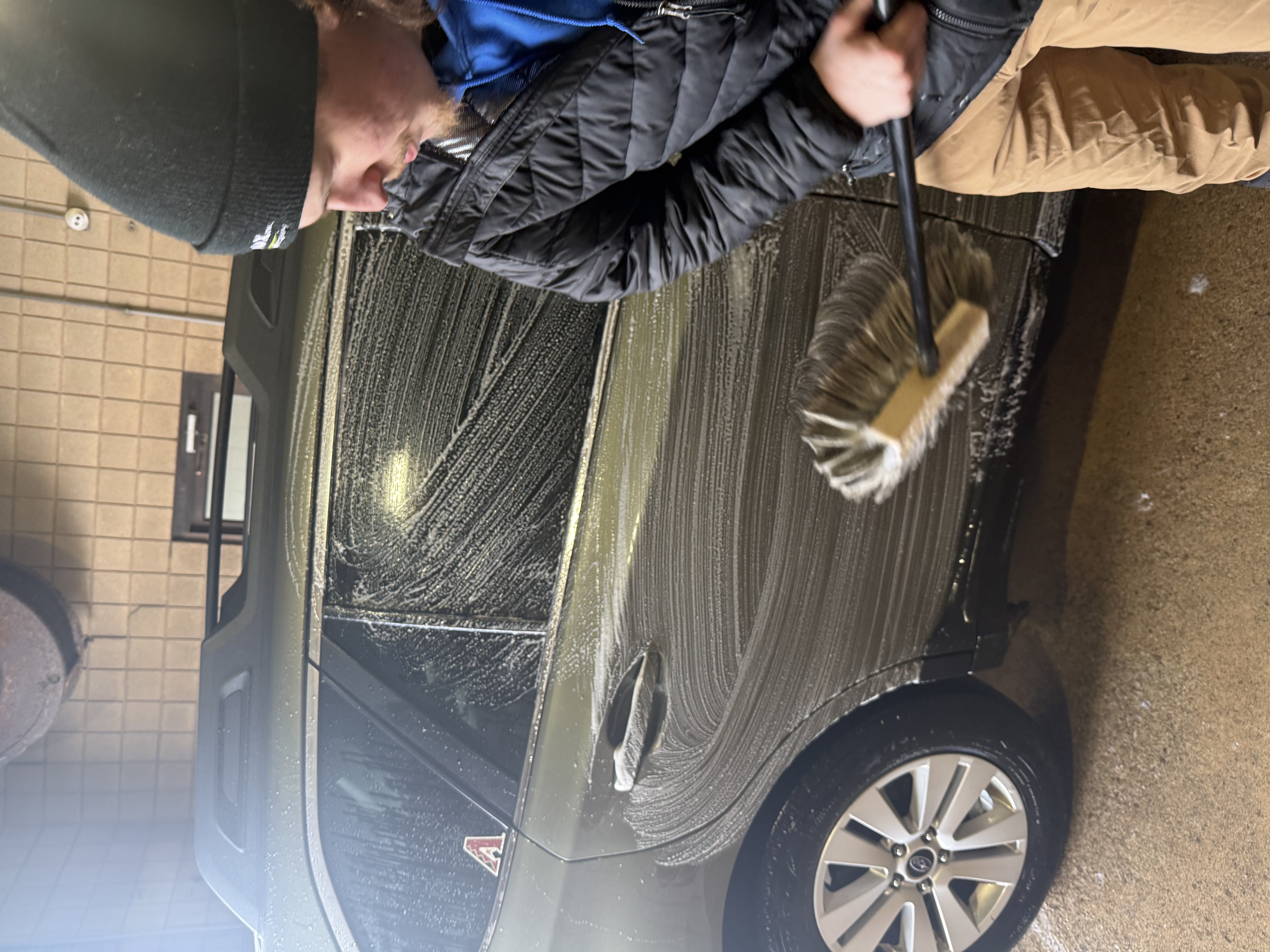 Team member hand-washing the side of an SUV at All Seasons Car Wash