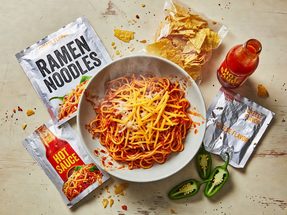 Finished chili cheese noodle spread in a bowl with ingredient packets nearby