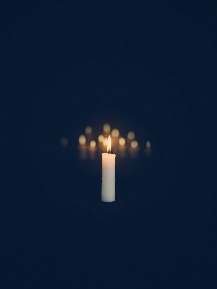 A single memorial candle glowing in darkness