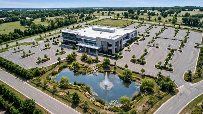 Aerial view of a commercial building beside a landscaped pond and fountain.