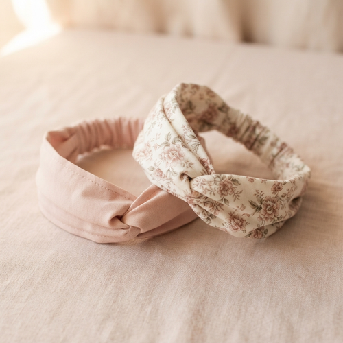 Two handmade fabric headbands in blush pink and ivory with floral texture on a warm ivory and blush background