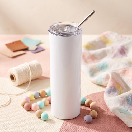 Plain white tumbler with a clear lid and metal straw surrounded by pastel beads and handmade craft materials
