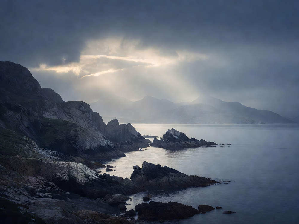 Rugged Argyll shoreline meeting calm grey-blue sea beneath a pearly overcast sky