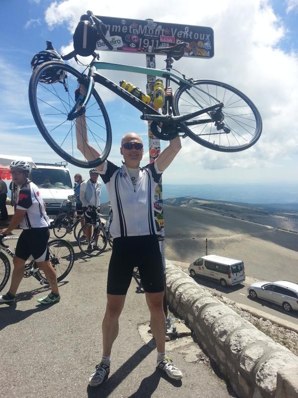 Cyclist holding a bicycle at a mountain pass