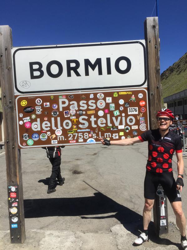 Cyclist celebrating beside the Bormio Passo dello Stelvio sign