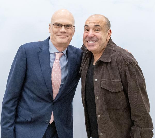 Two men posing together before an event backdrop