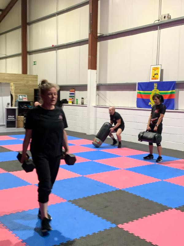 Warrior Fitness class members performing weighted conditioning exercises in the training space