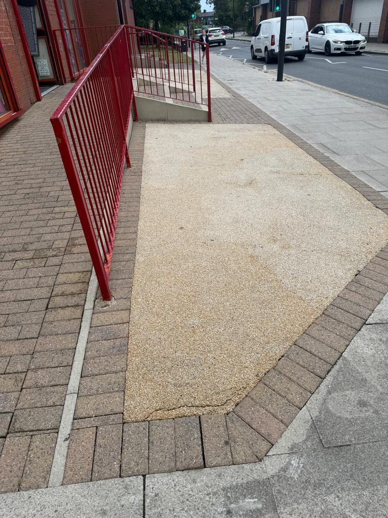 After photo of a wider paved commercial frontage and entrance following clean-up work
