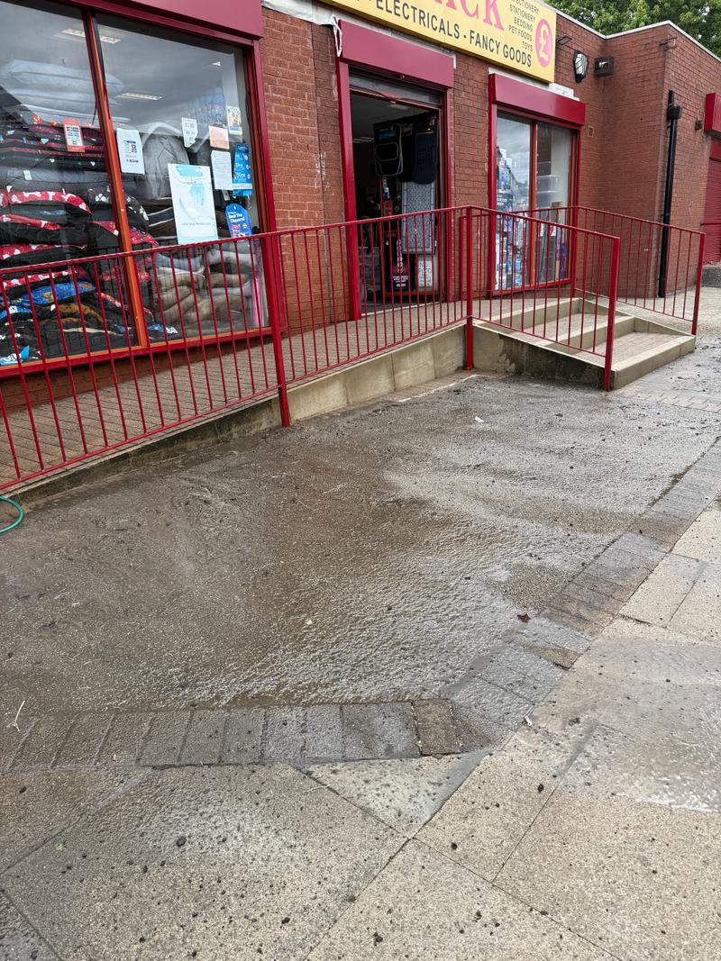 Before photo of a wider paved commercial frontage and entrance