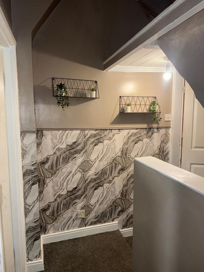 After photo of a decorated interior hallway and landing with painted walls and a patterned lower wall