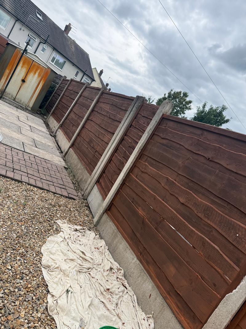 After photo of a darker brown painted timber fence in an outdoor area