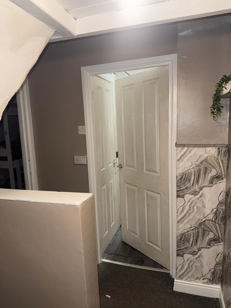 After photo of a decorated hallway and landing with painted walls, shelves and a patterned feature wall