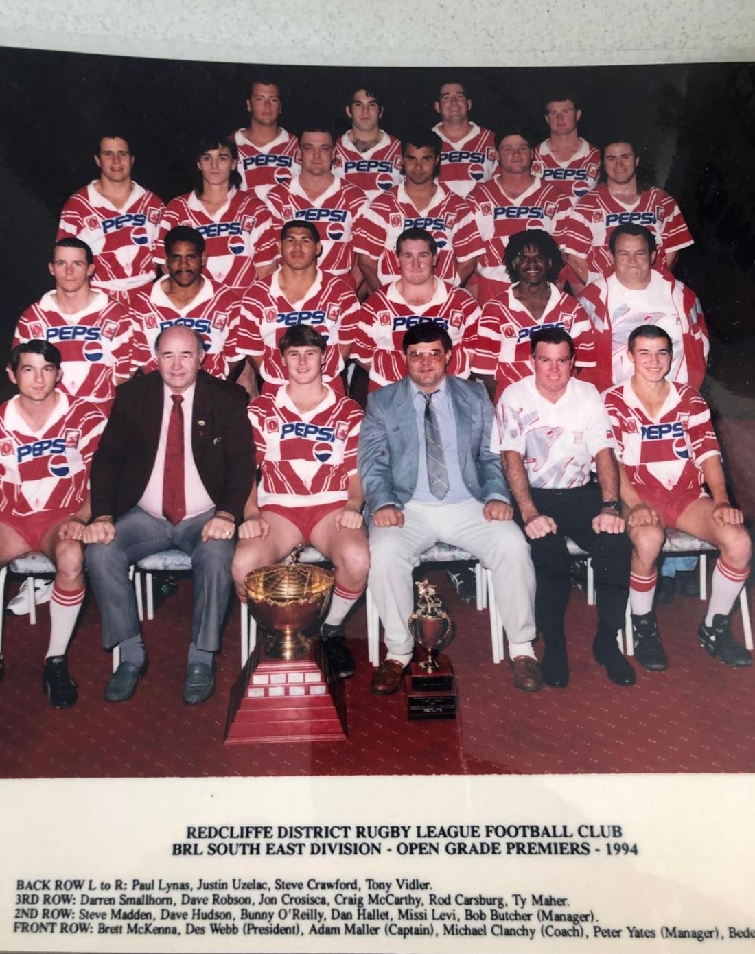 Misi and his teammates in a full red-and-white team portrait, with the Redcliffe District Rugby League Football Club 1994 BRL South East Division Open Grade Premiers inscription printed below.