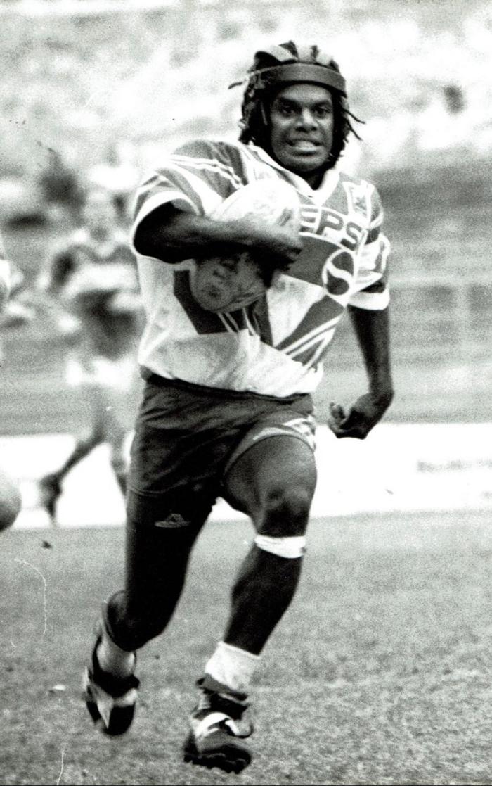 Misi running forward with the football in a black-and-white rugby league photograph.
