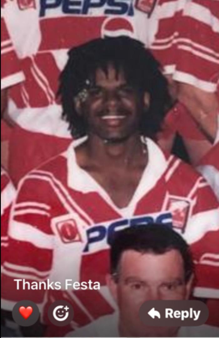 Misi smiling in a red-and-white rugby league jersey, with other players in matching jerseys behind him.
