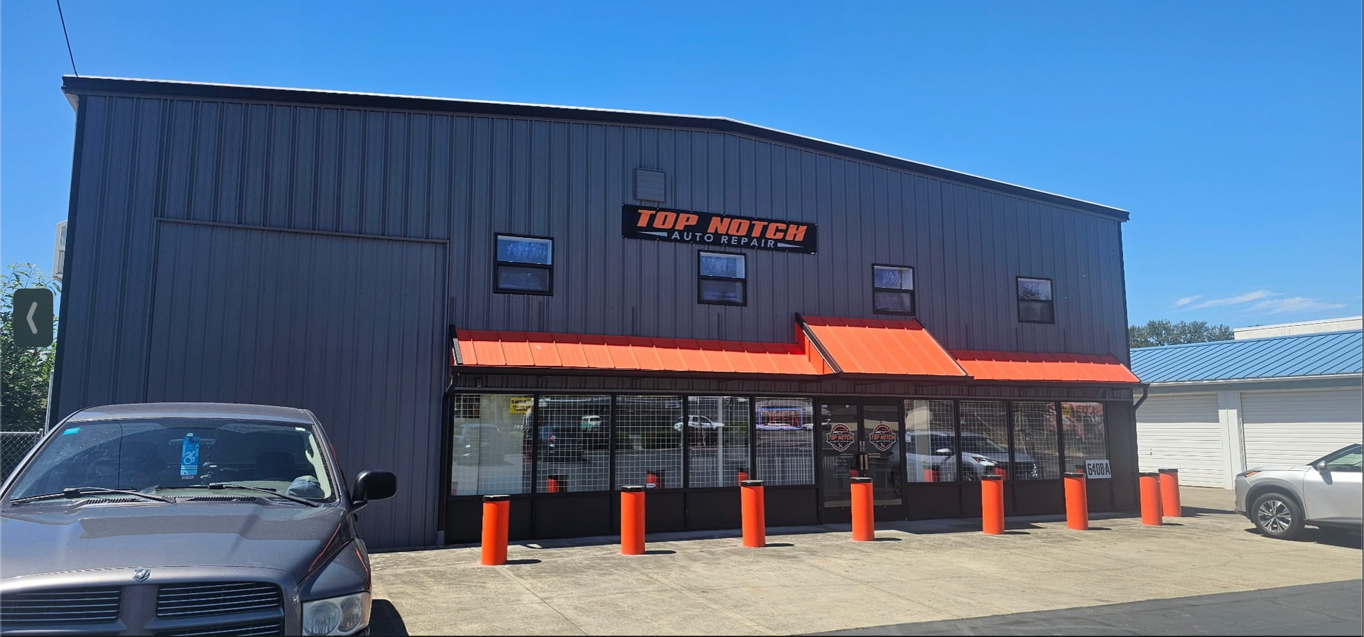 Top Notch Auto Repair exterior at 6408 NE St. John's Rd in Vancouver WA with dark metal siding, orange awnings and Top Notch Auto Repair signage