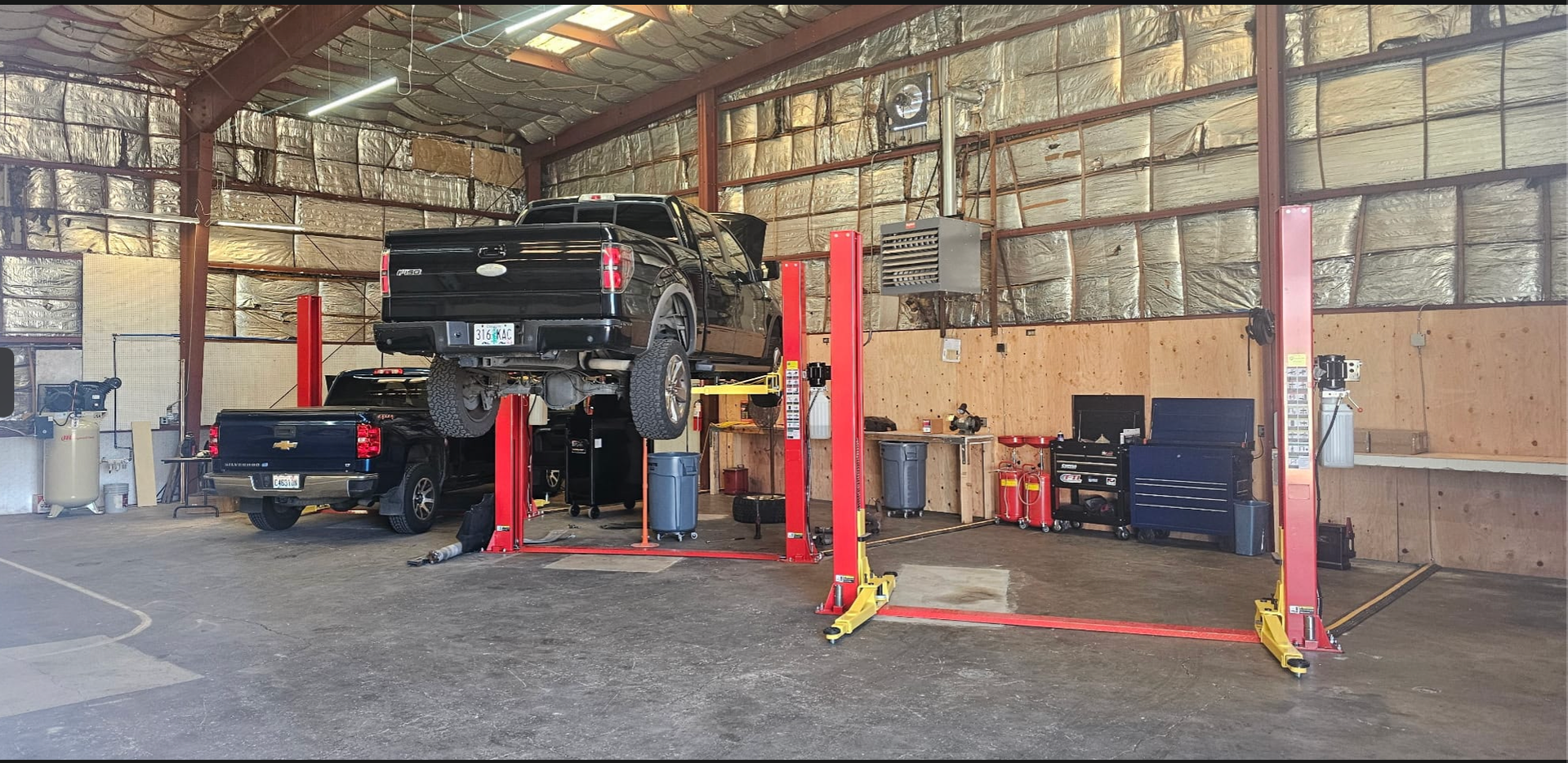 Real repair bay at Top Notch Auto Repair Vancouver WA with trucks lifted on red lifts and organized shop equipment