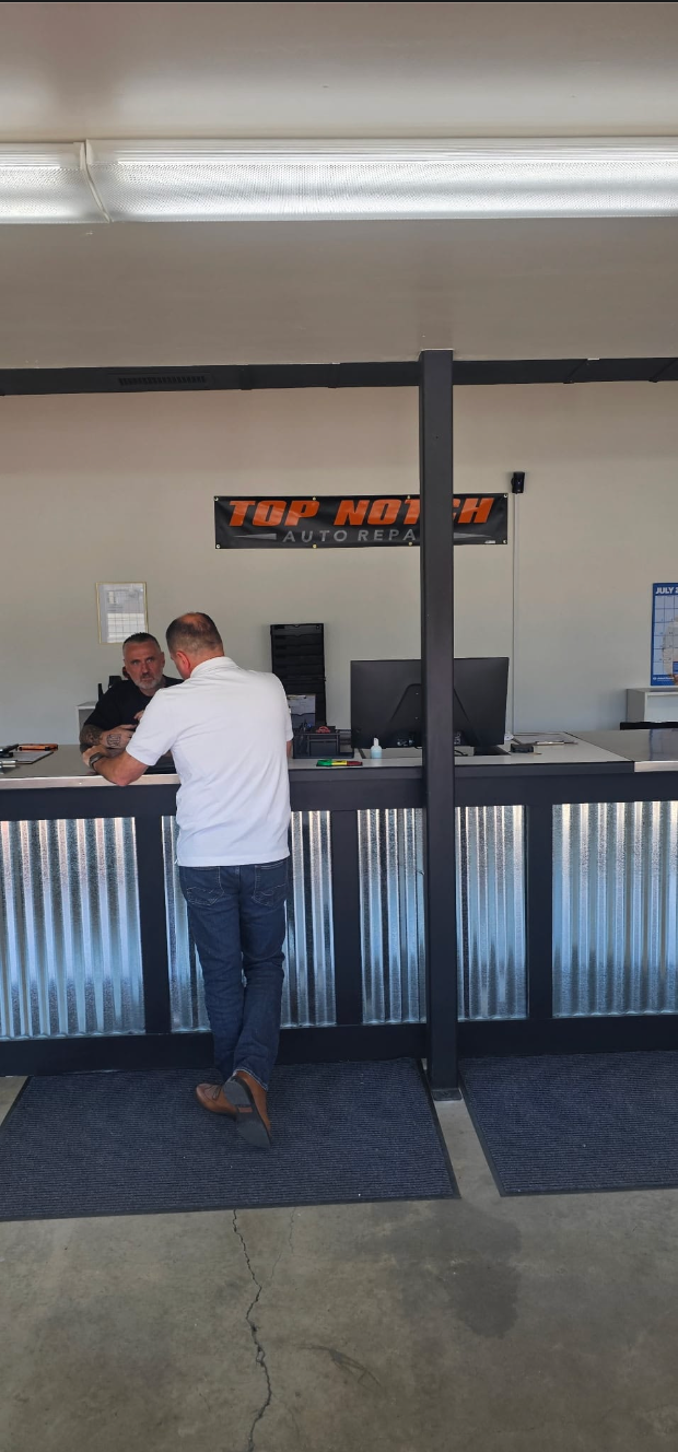 Top Notch advisor speaking with a customer at the front counter with shop banner visible in Vancouver WA