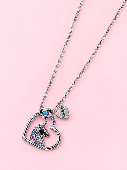 Silver initial necklace with a colorful unicorn heart pendant and an I charm on a pink background