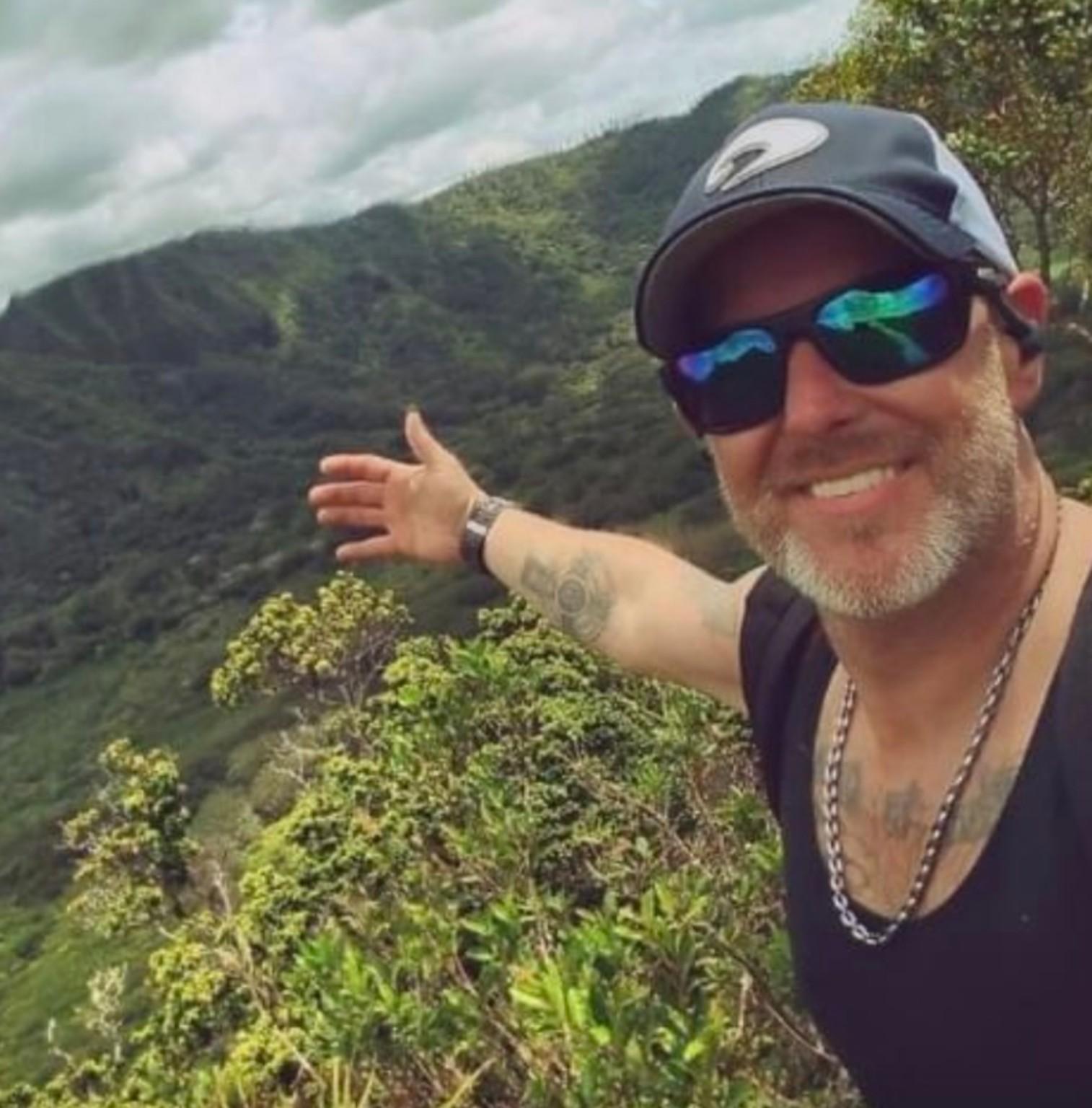 Josh Alexander overlooking the green mountains beyond Manoa Falls on Oahu, Hawaii
