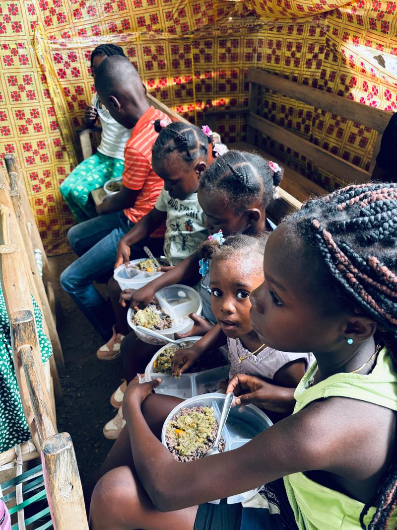 Children share prepared meals during community care in Haiti