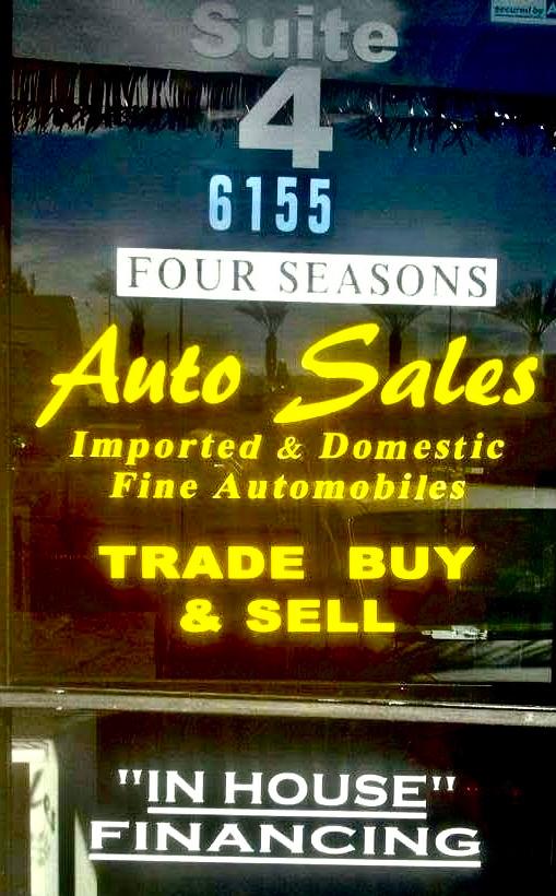Yellow Four Seasons Auto Sales lettering across storefront glass in Suite 4, with trade, buy, and sell information.