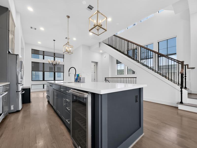 Large kitchen island in a bright open home with a staircase.