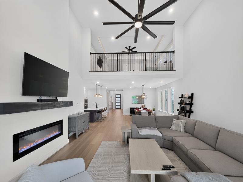 Two-story living room with a sectional, fireplace, and open railing.