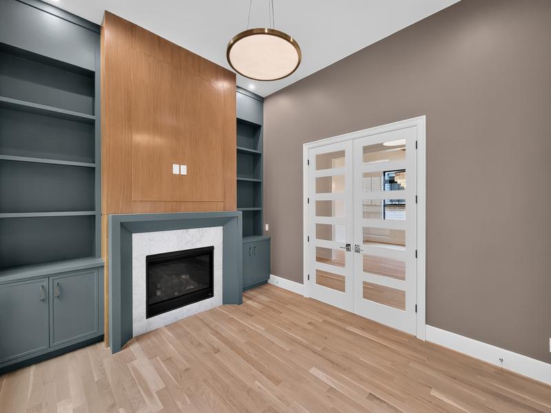 Fireplace and built-in shelving in a room with wood floors.