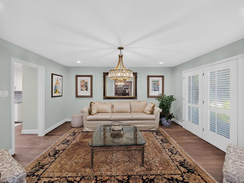 Living room with a cream sofa, chandelier, and shuttered windows.