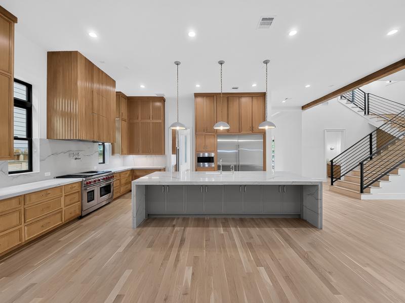 Kitchen with a broad island, wood cabinets, and staircase.