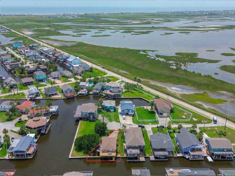 Aerial view of waterfront homes and marshland, with one property outlined in red.