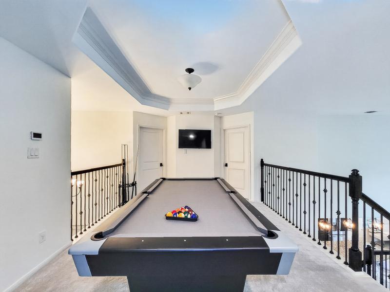Upstairs game room with a billiards table and open railing.