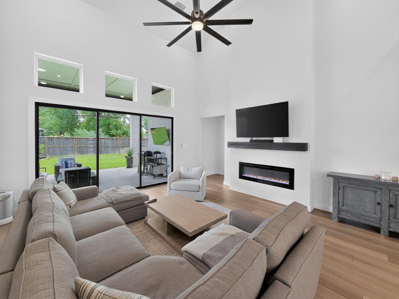 Open living room with a sectional sofa, fireplace, and glass doors.