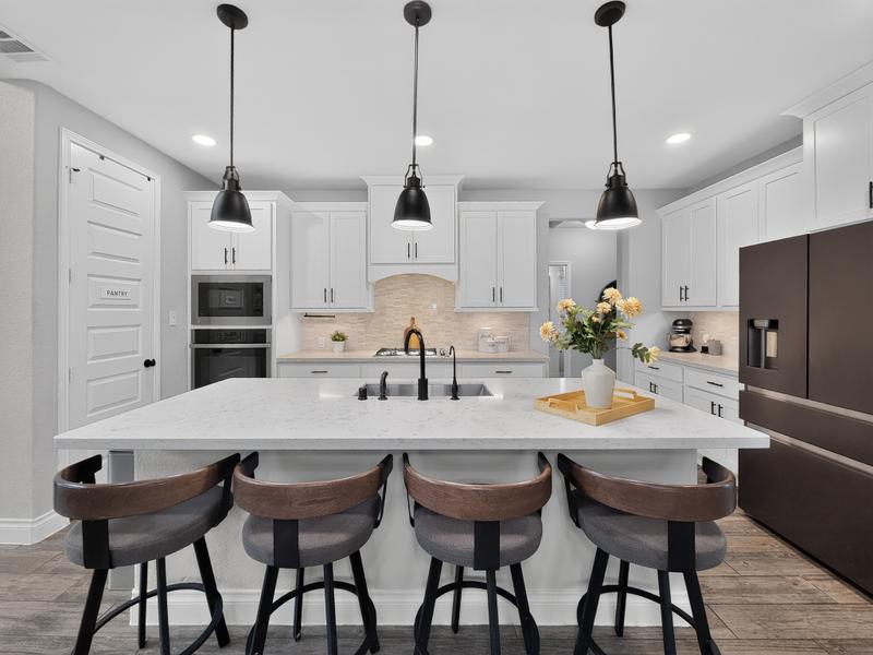 Bright kitchen with a large island and dark pendant lights.