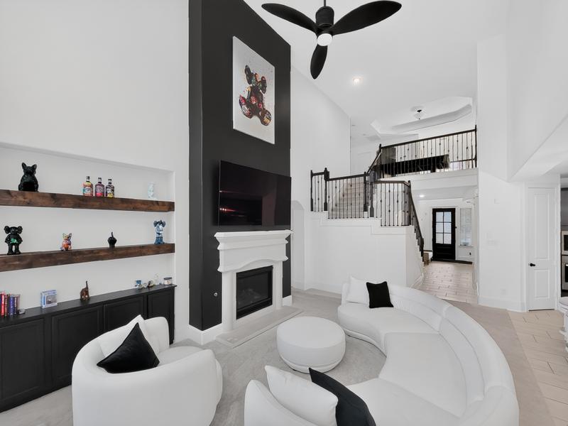 Living room with curved white seating, a dark fireplace wall, and staircase.