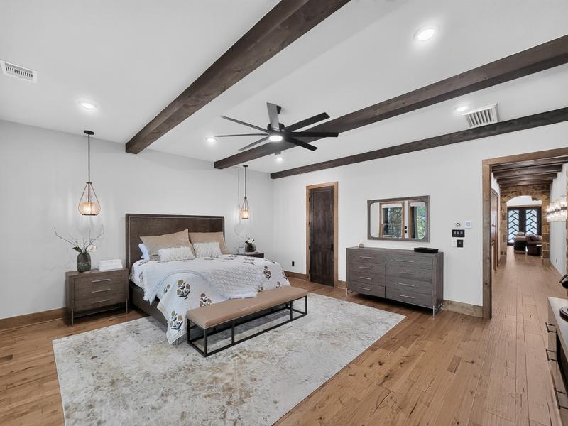 Bedroom with a large bed, exposed wood beams, and ceiling fan.