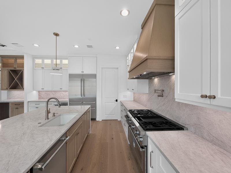 Kitchen with an island, light cabinets, and a stainless range hood.
